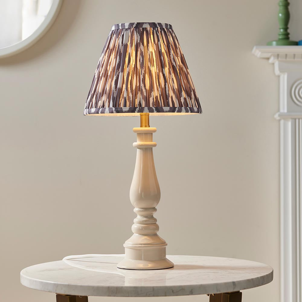 Endon Carlworth Ikat table lamp with almond gloss turned resin spindle base and grey pleated Ikat shade, on a marble side table by a mirror.
