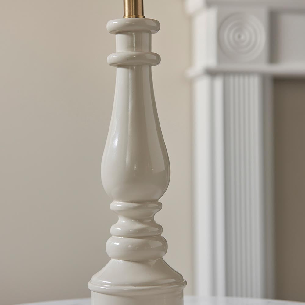 Close-up of the Endon Carlworth Ikat table lamp base in high gloss almond resin, turned spindle shape with brass fitting, beside a white fireplace.