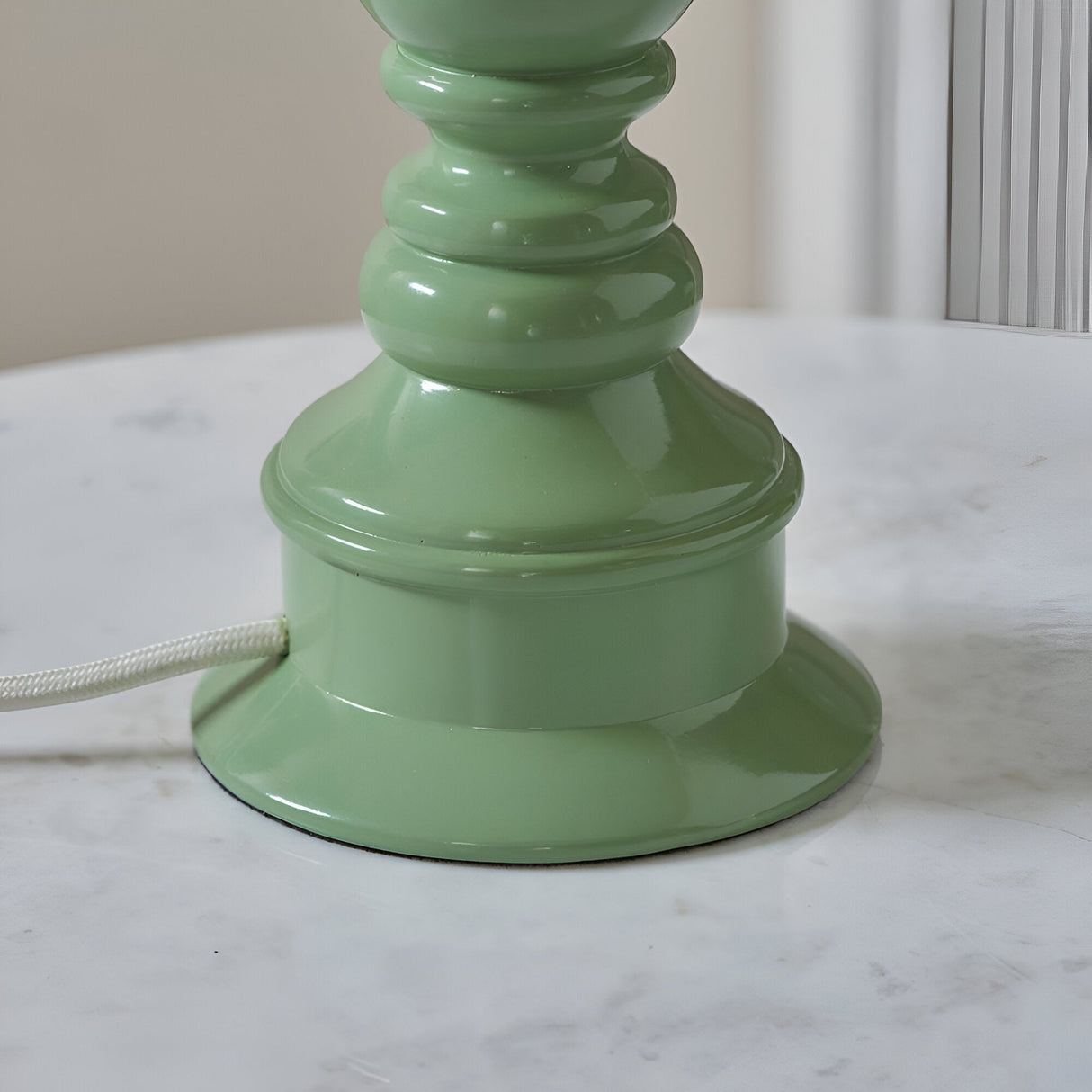 Carlworth Zigzag Table Lamp base close-up in Cotswold Green resin with turned spindle shape and white fabric cord, shown on a marble surface.