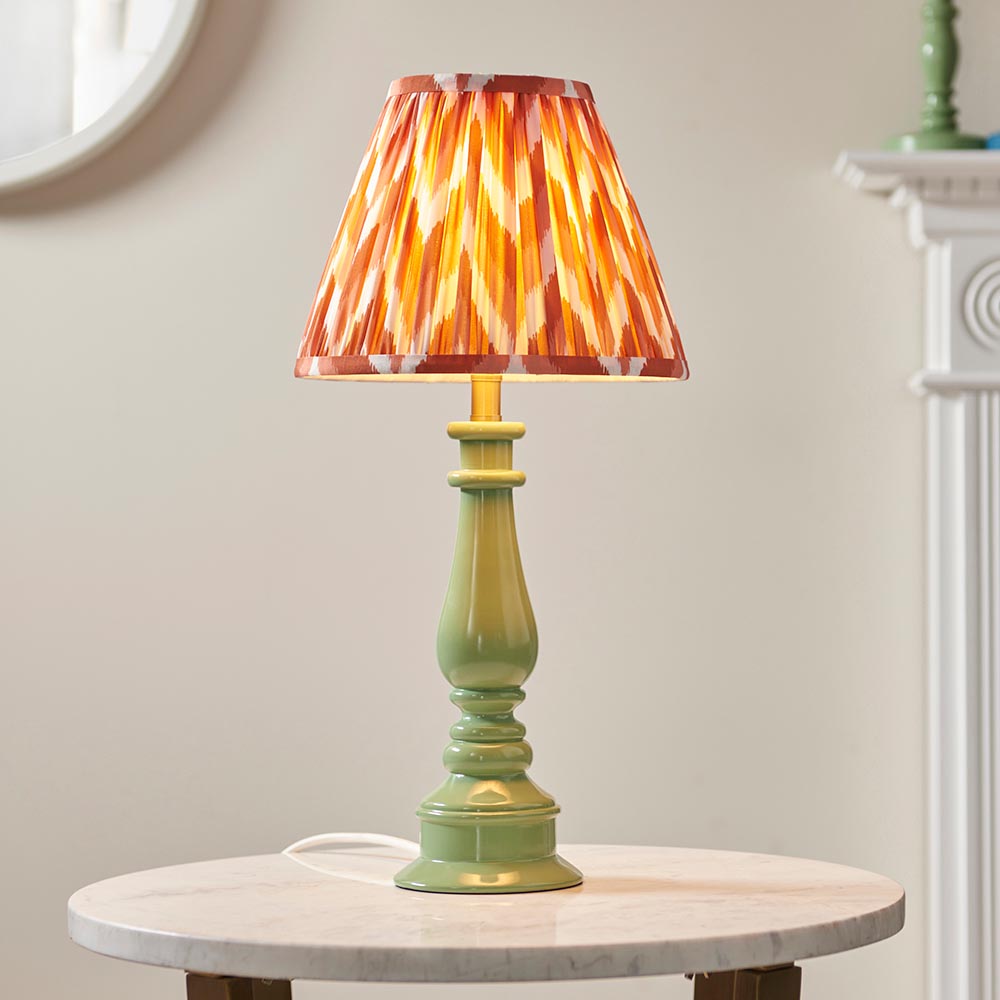 Carlworth Zigzag Table Lamp with green resin spindle base and pleated apricot zigzag-print shade, shown on a marble side table.
