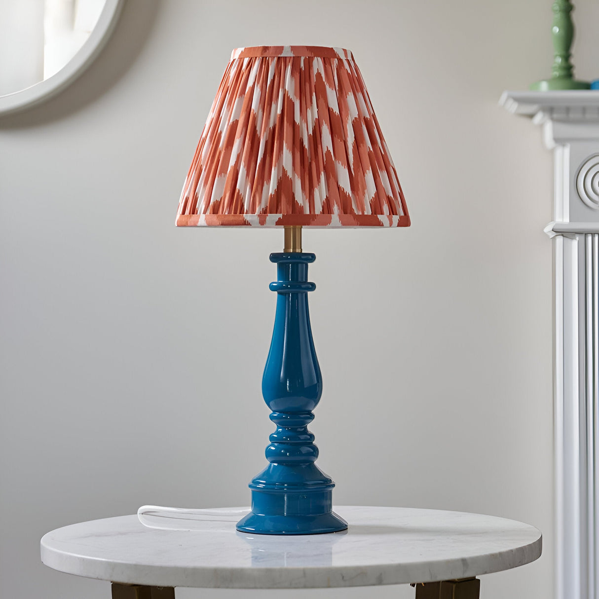 Endon Carlworth Zigzag table lamp with marlin blue turned resin spindle base and pleated apricot zigzag shade, on a marble side table.