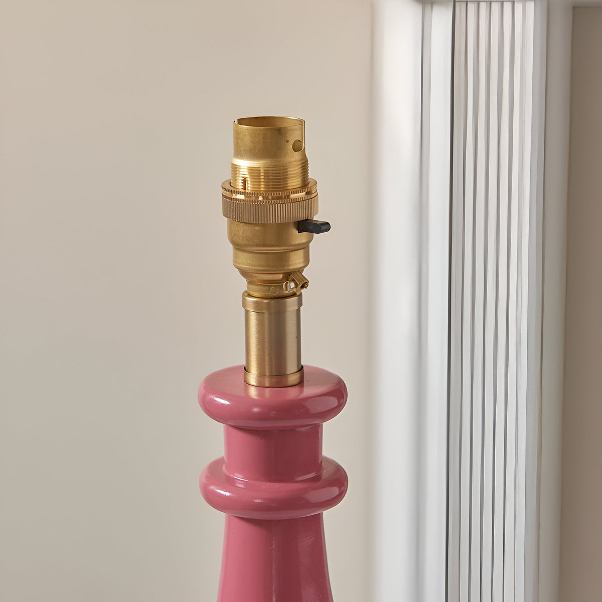 Endon Carlworth Ivy table lamp close-up showing the brass B22 switched lamp holder above a glossy pink turned resin spindle base.