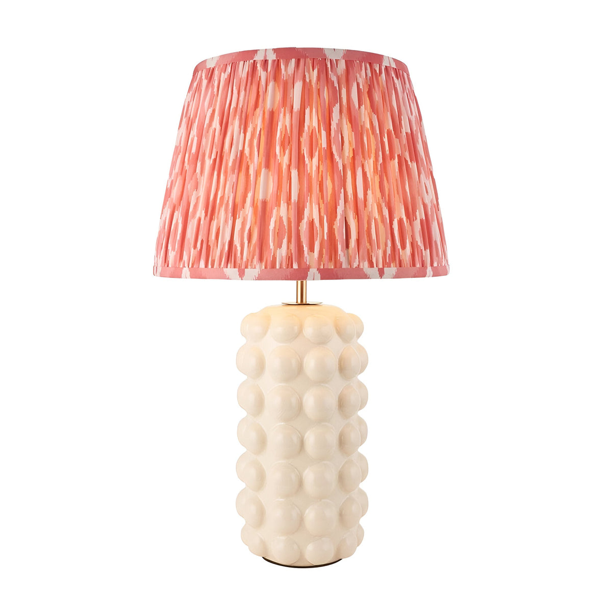 Amberley Ikat table lamp with a white ceramic bobble base and a pleated pink and white patterned Ikat shade, brass stem detail, on a plain white background.