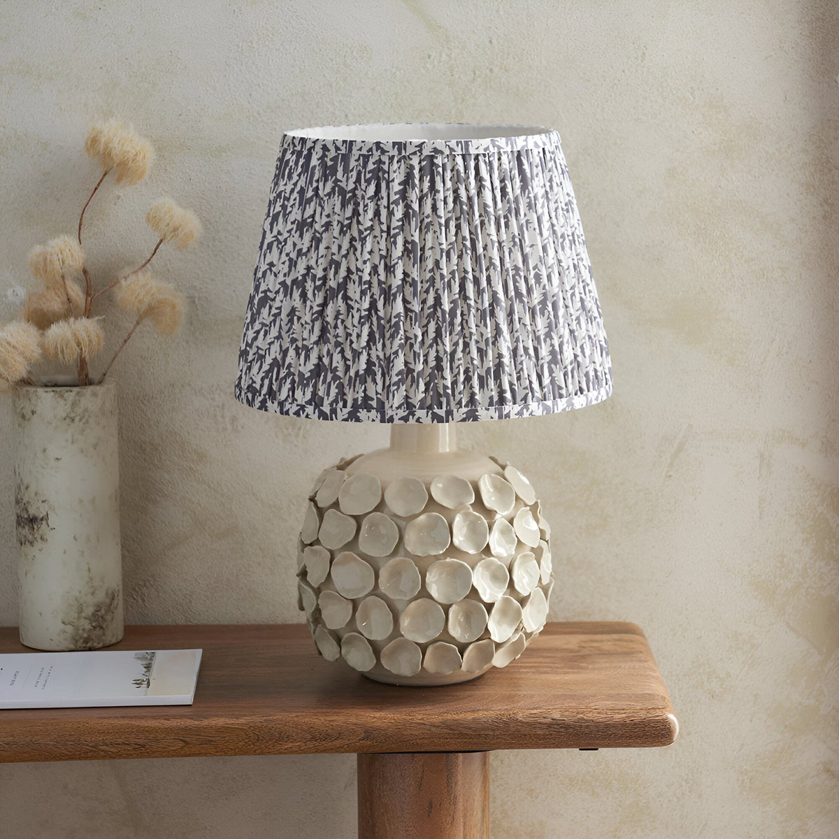 Ashbury Leaf Table Lamp in grey, ceramic disc-textured base with pleated leaf-patterned shade, shown on a wooden console table.
