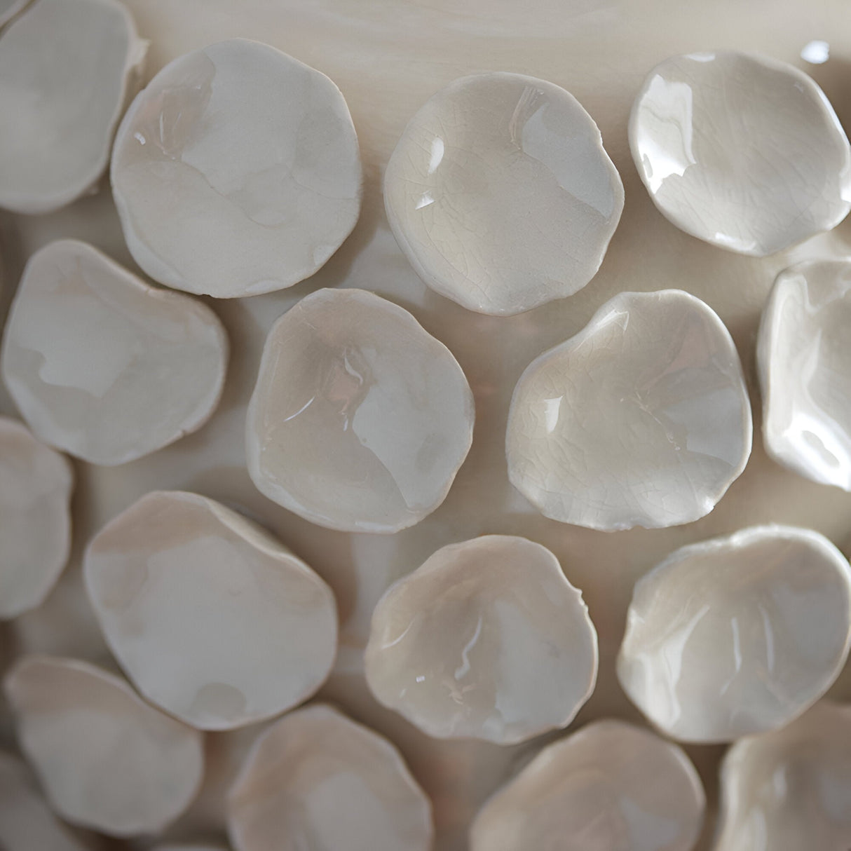 Close-up of the Ashbury table lamp's ceramic base, showing sculptured petal-like forms in an ivory crackle glaze finish.