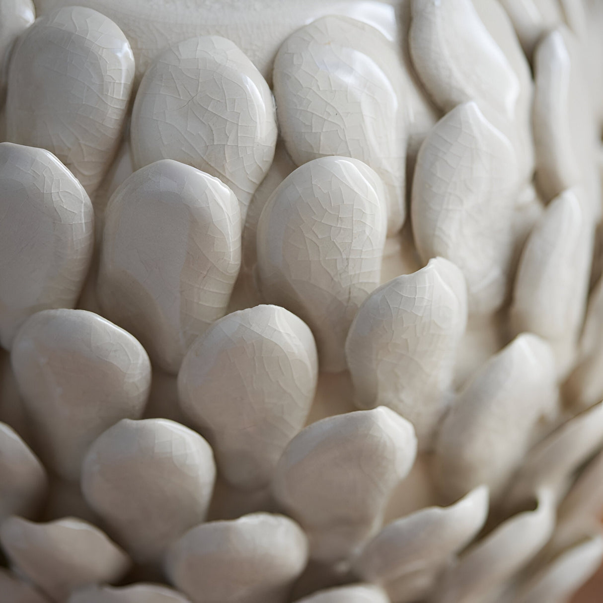Close-up of the Endon Caldford table lamp's ceramic base, showing handmade leaf-shaped details in an ivory crackle glaze.