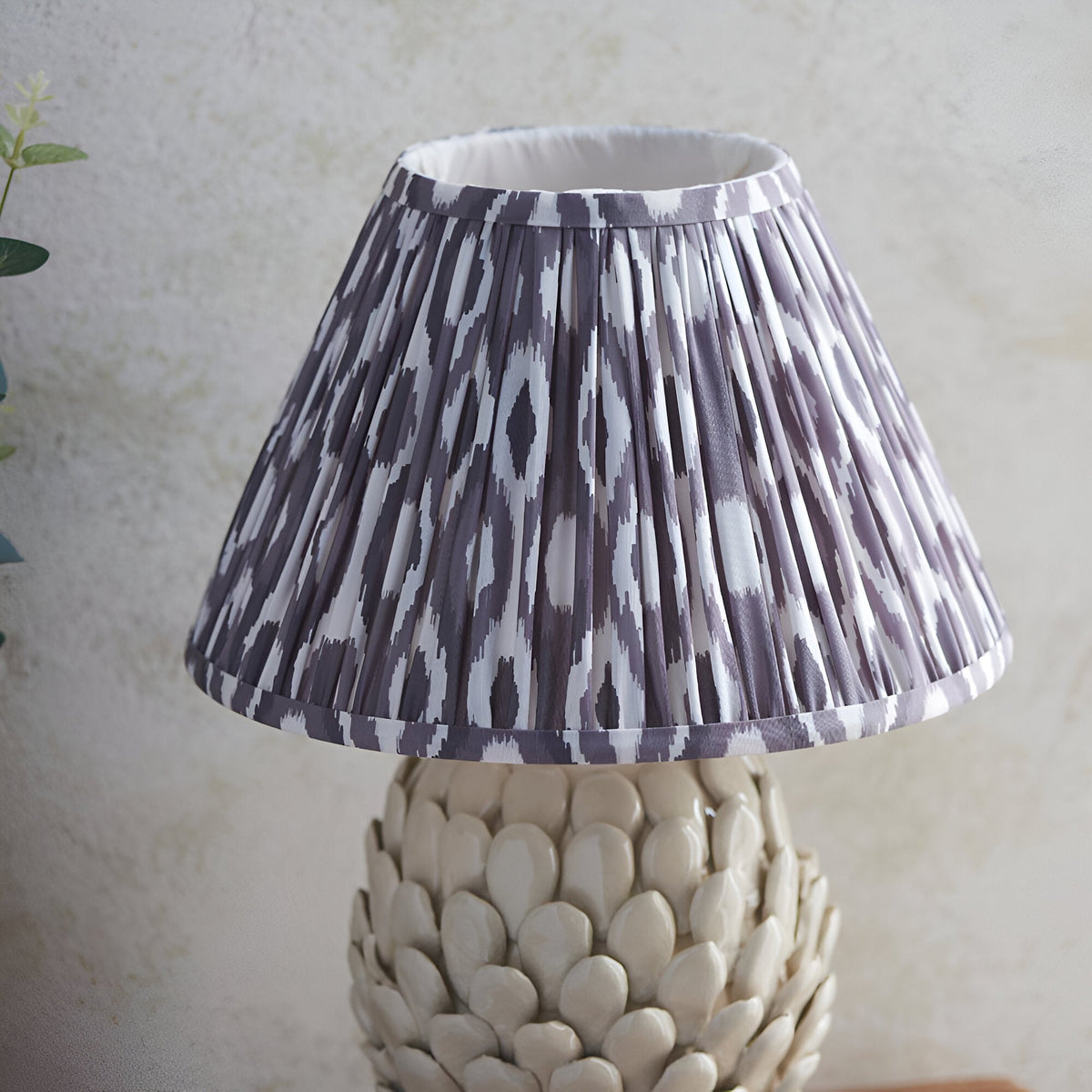 Endon Caldford table lamp with pleated grey and white Ikat fabric shade above an ivory crackle-glaze ceramic base with sculpted leaf detailing.