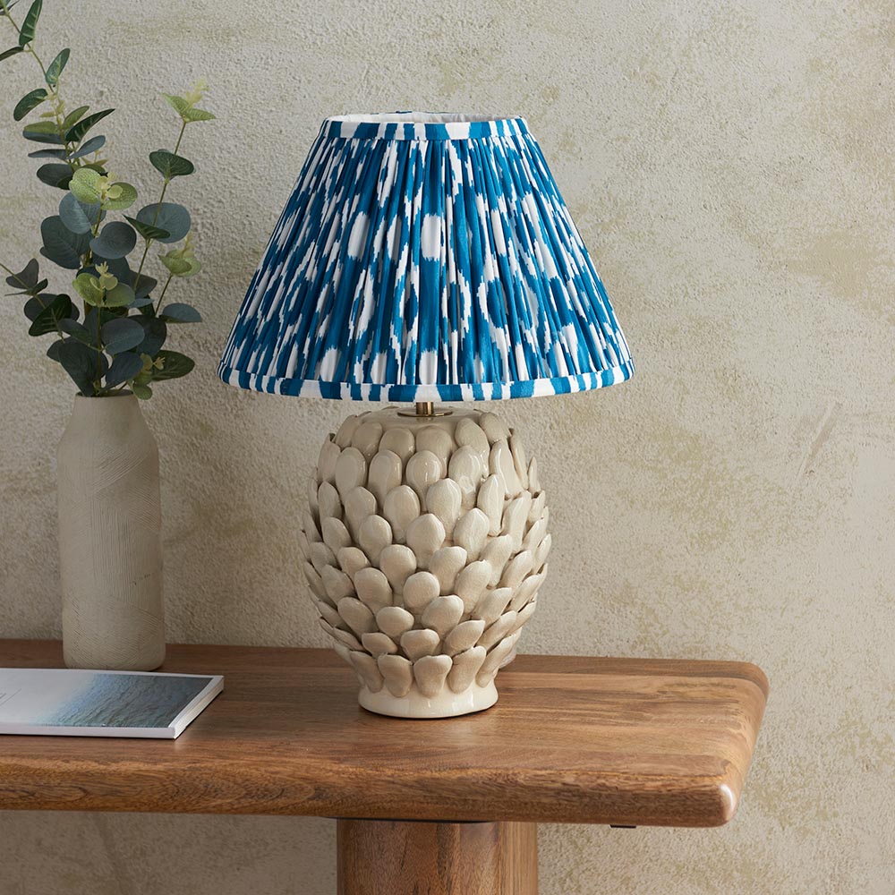 Caldford Ikat 30cm Table Lamp with ceramic leaf-textured cream base and blue-white patterned shade, styled on a wooden console table with a vase.