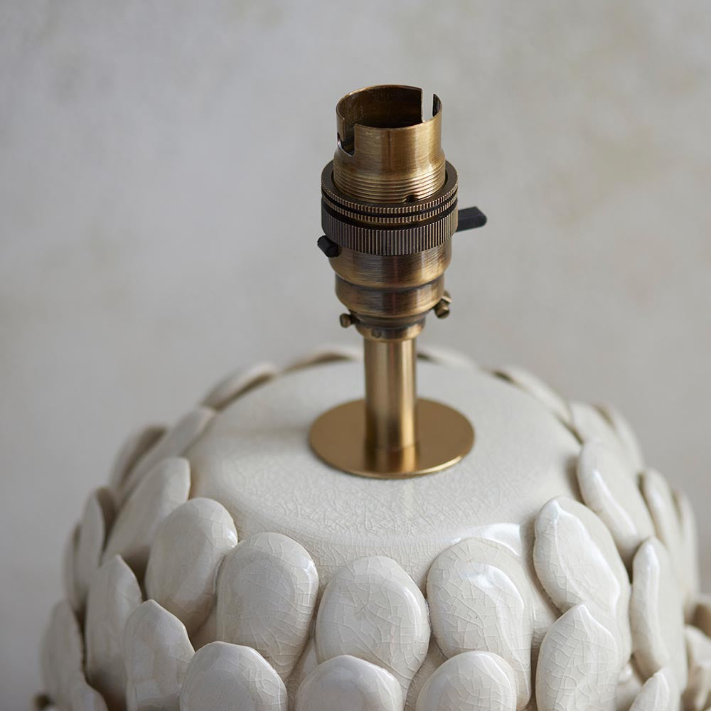 Caldford Ikat table lamp base close-up, ceramic leaf-textured cream body with aged brass switched B22 bayonet lamp holder.