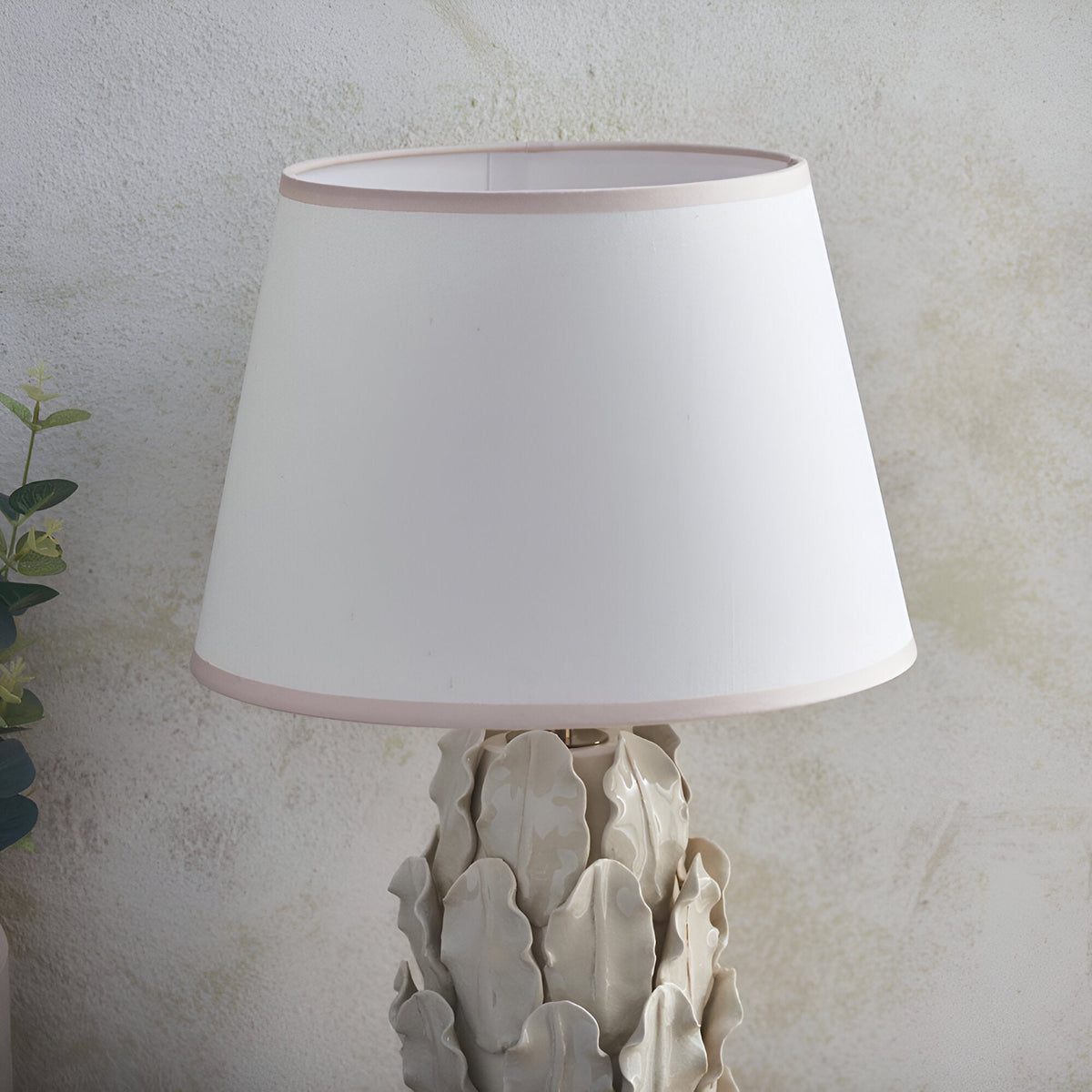 Caldford Ivy 35cm table lamp with ivory crackle-glazed ceramic leaf-detail base and white tapered fabric shade with pink trim.