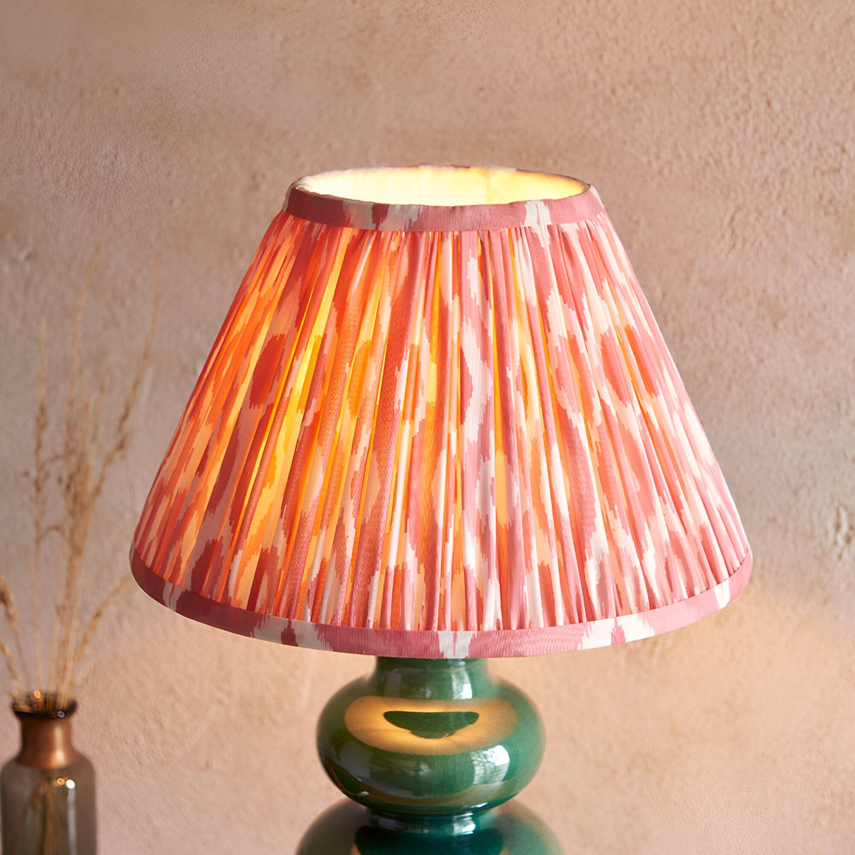 Carlstead Ikat Table Lamp with glossy dark green ceramic gourd-shaped base and pleated pink and orange patterned fabric shade.