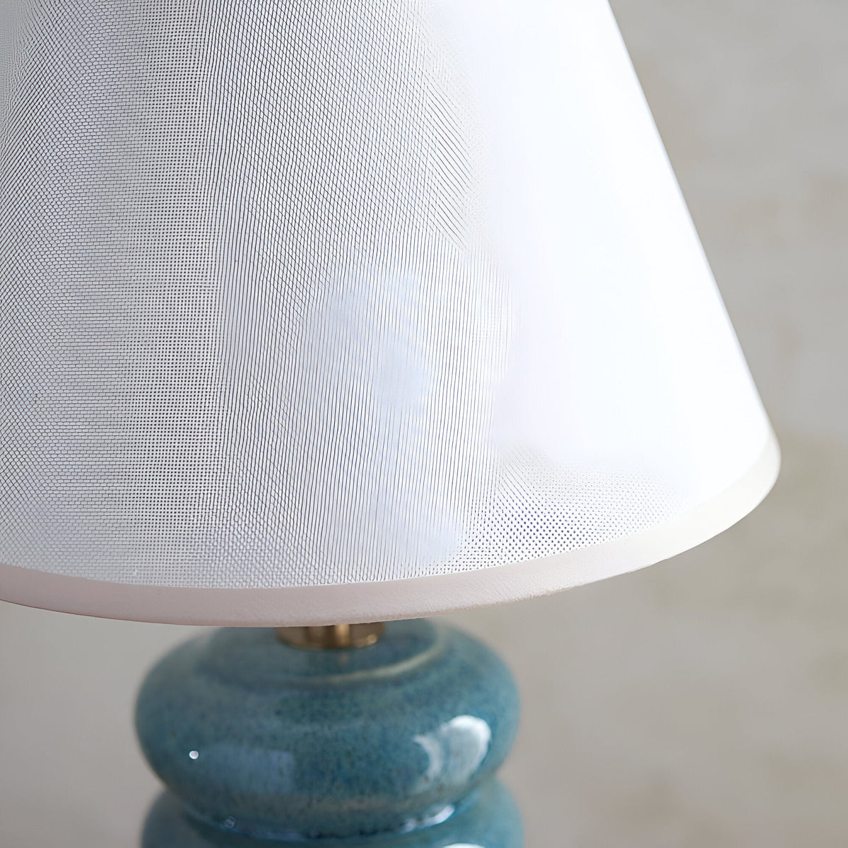 Close-up of the Endon Cliffstead table lamp showing the vintage white Ivy fabric shade, aged brass fitting, and ocean spray blue-green ceramic base.