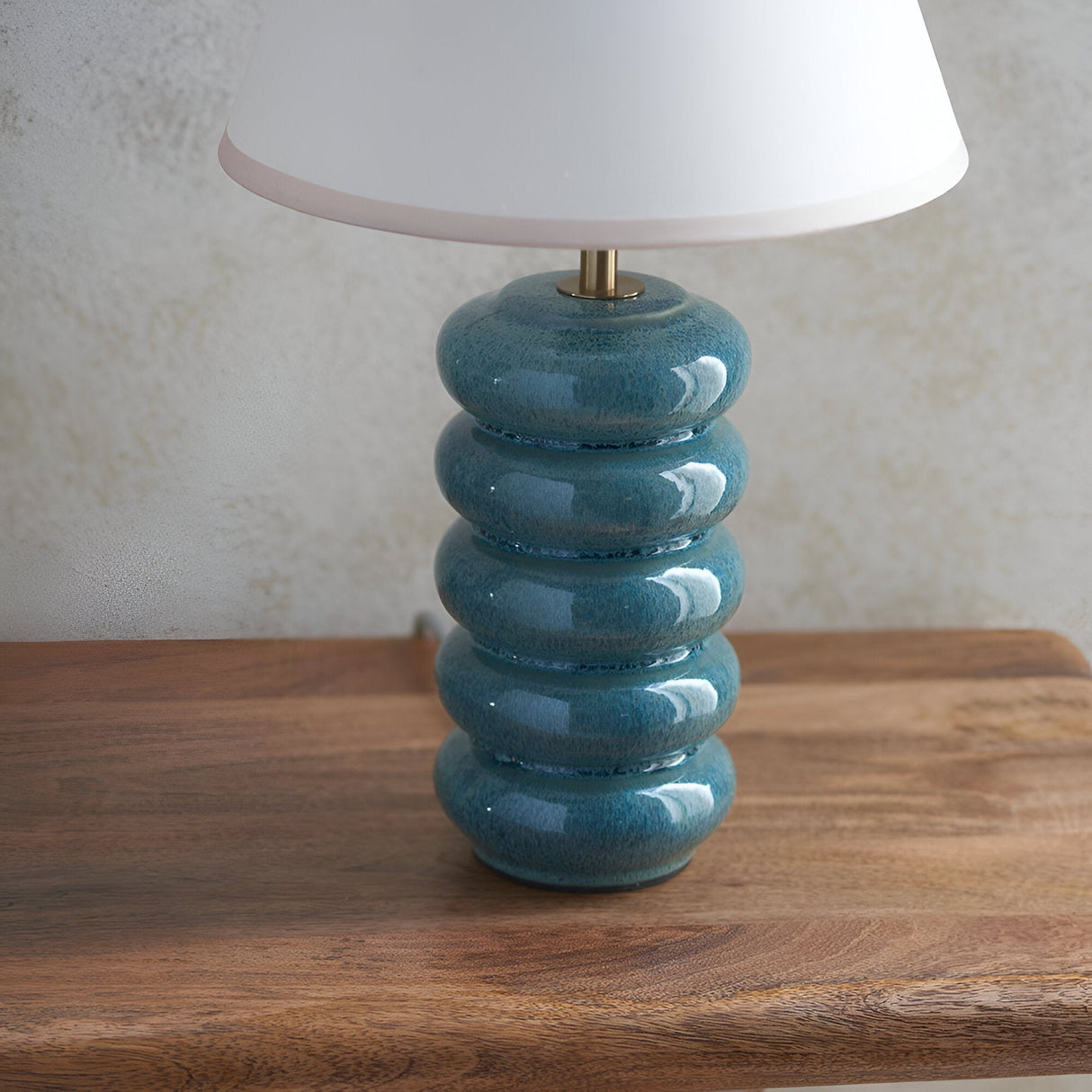 Endon Cliffstead ceramic table lamp with stacked ocean spray blue-green glazed base, antique brass stem and white Ivy shade on a wooden surface.
