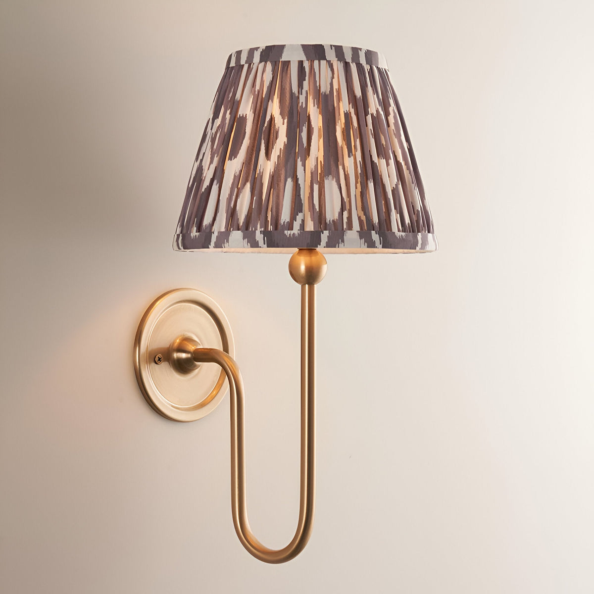 Cliffleigh Ikat Wall Light in Dark Grey with an antique brass wall-mounted arm and pleated tapered fabric shade, shown against a plain light background.