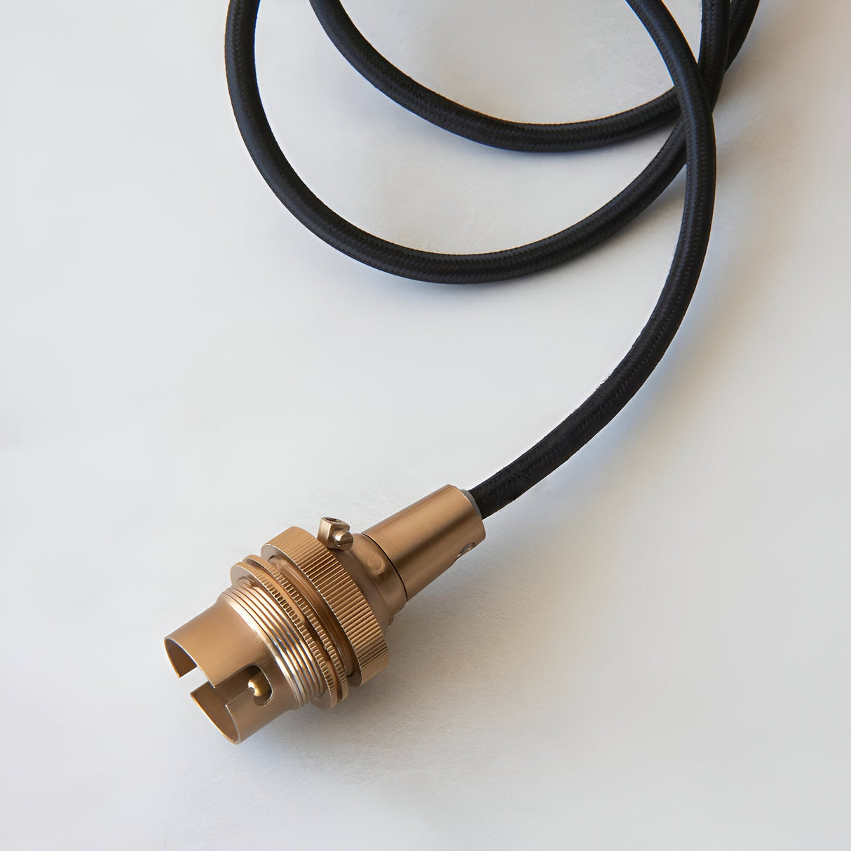 Endon Brackmont Flex Set pendant with brushed aged brass B22 lampholder and coiled black braided fabric cable on a plain white background.