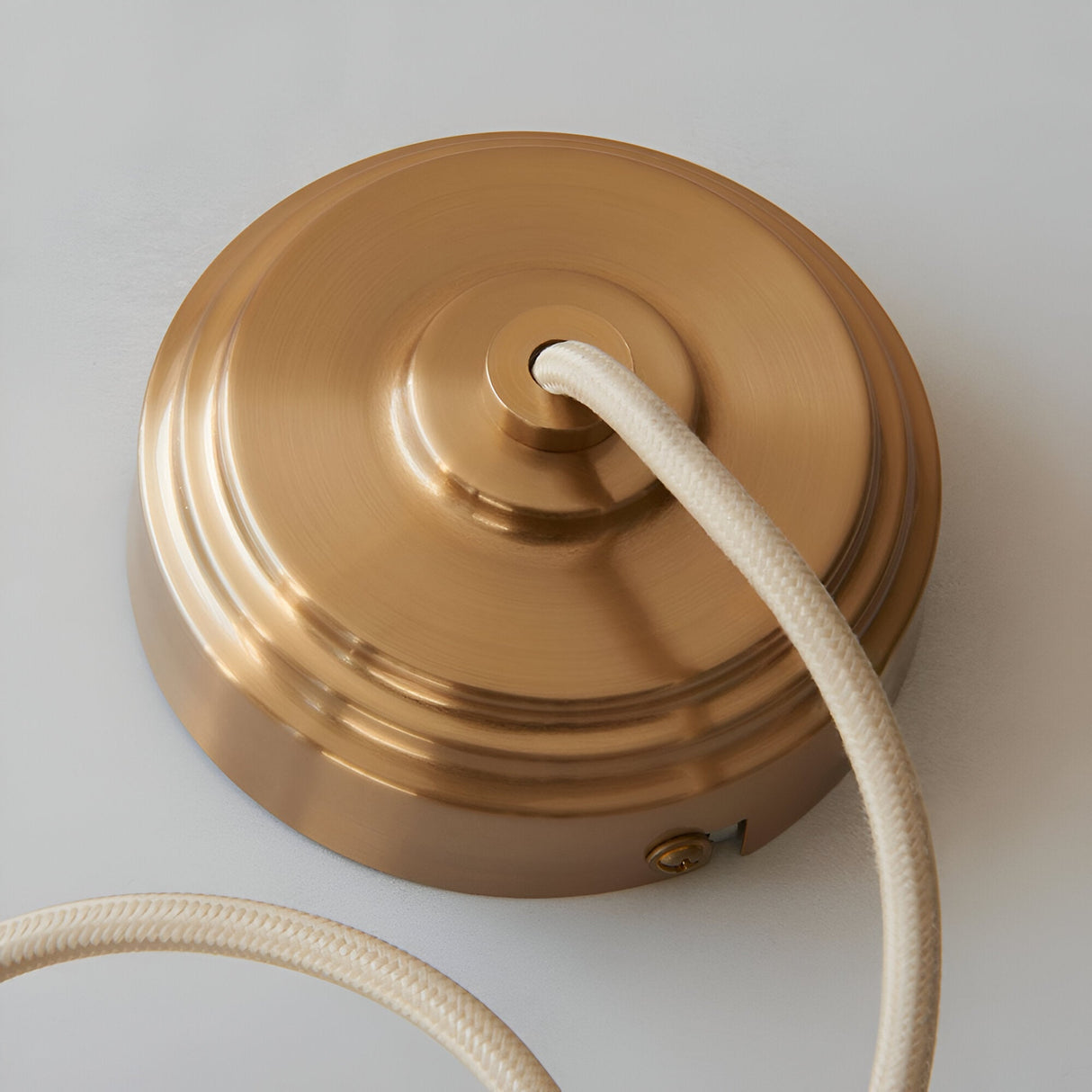 Endon Brackmont pendant flex set ceiling rose in brushed aged brass with natural braided fabric cable, shown against a light background.