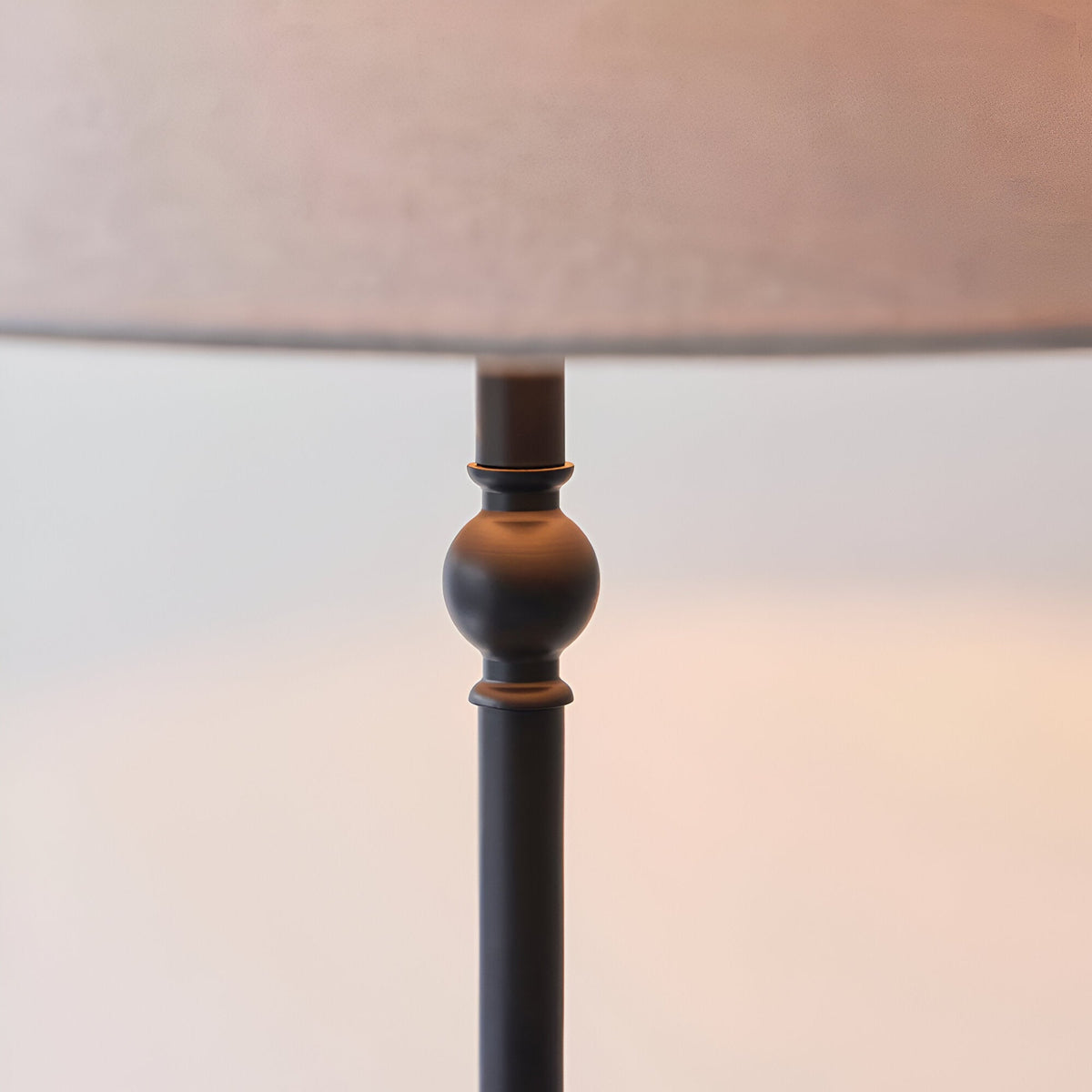 Close-up of the Endon Caldmere floor lamp's matt black metal stem with a decorative spherical detail beneath a natural linen tapered shade.