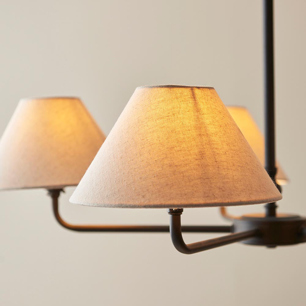 Close-up of Endon Caldmere 5 Light Large Pendant in black with tapered natural linen shades on slim matt black arms, shown lit against a pale background.