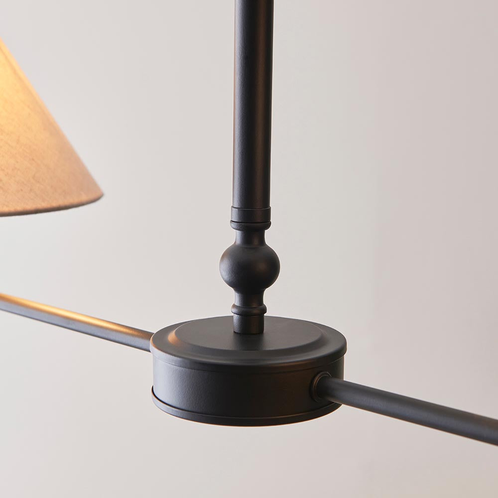 Close-up of the Endon Caldmere 2 Light Pendant showing the matt black telescopic stem, central ball detail, disc fitting, and edge of a natural linen shade.