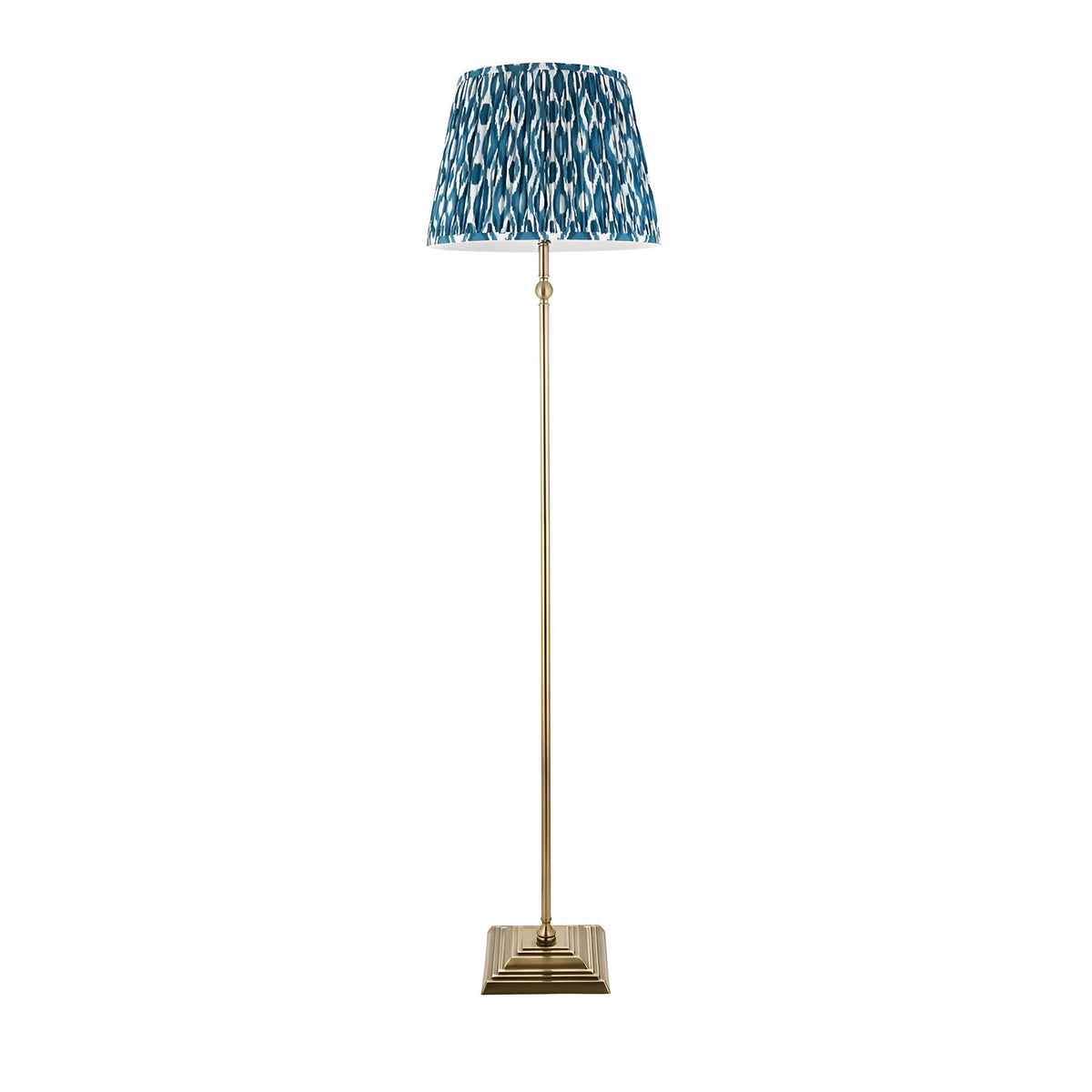 Endon Caldmere floor lamp with antique brass stepped square base, slim stem and pleated marlin blue Ikat fabric shade, on a plain white background.