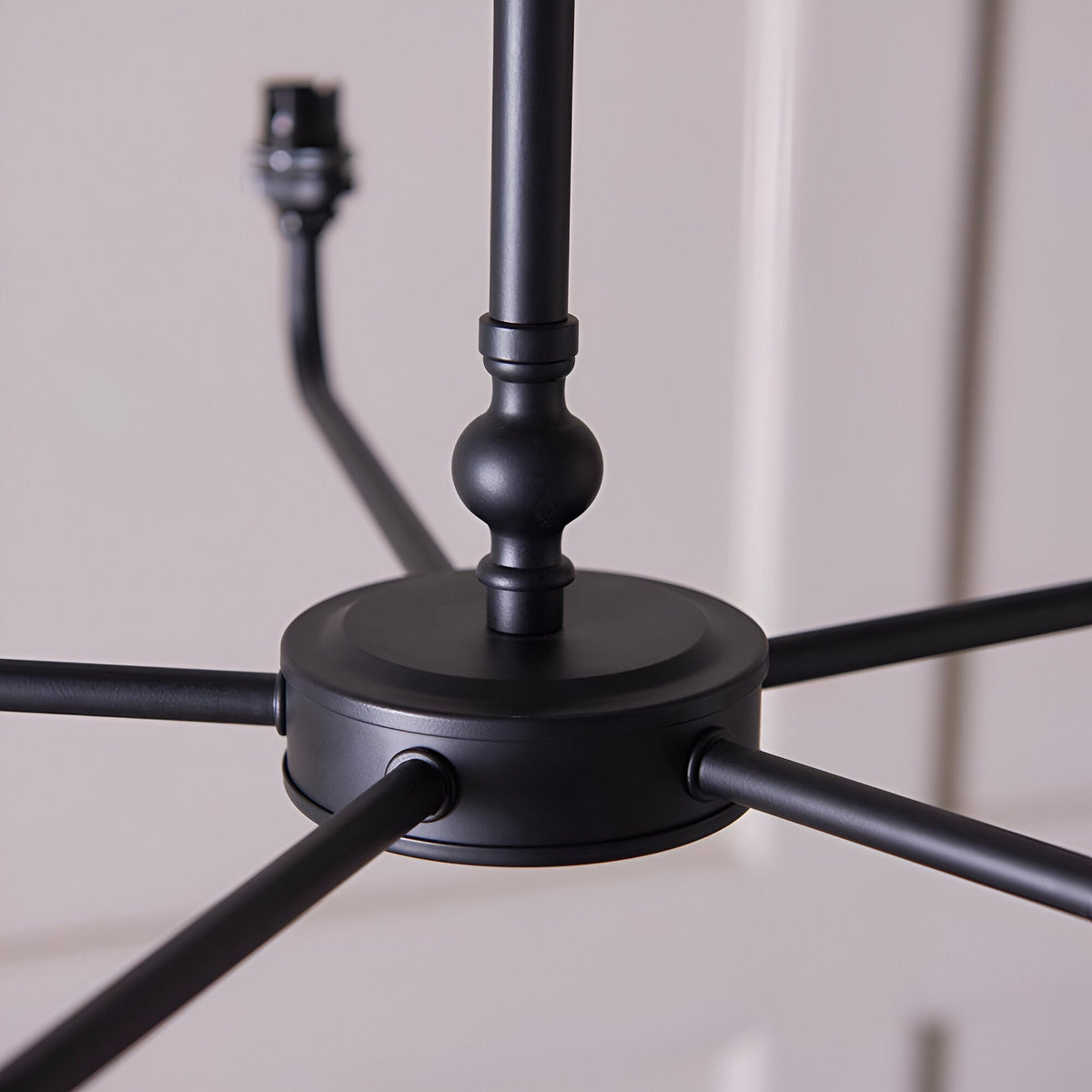 Caldmere 5 Light Ikat Pendant close-up of matt black metal centre hub with five splayed arms and ball-jointed ceiling rod detail.