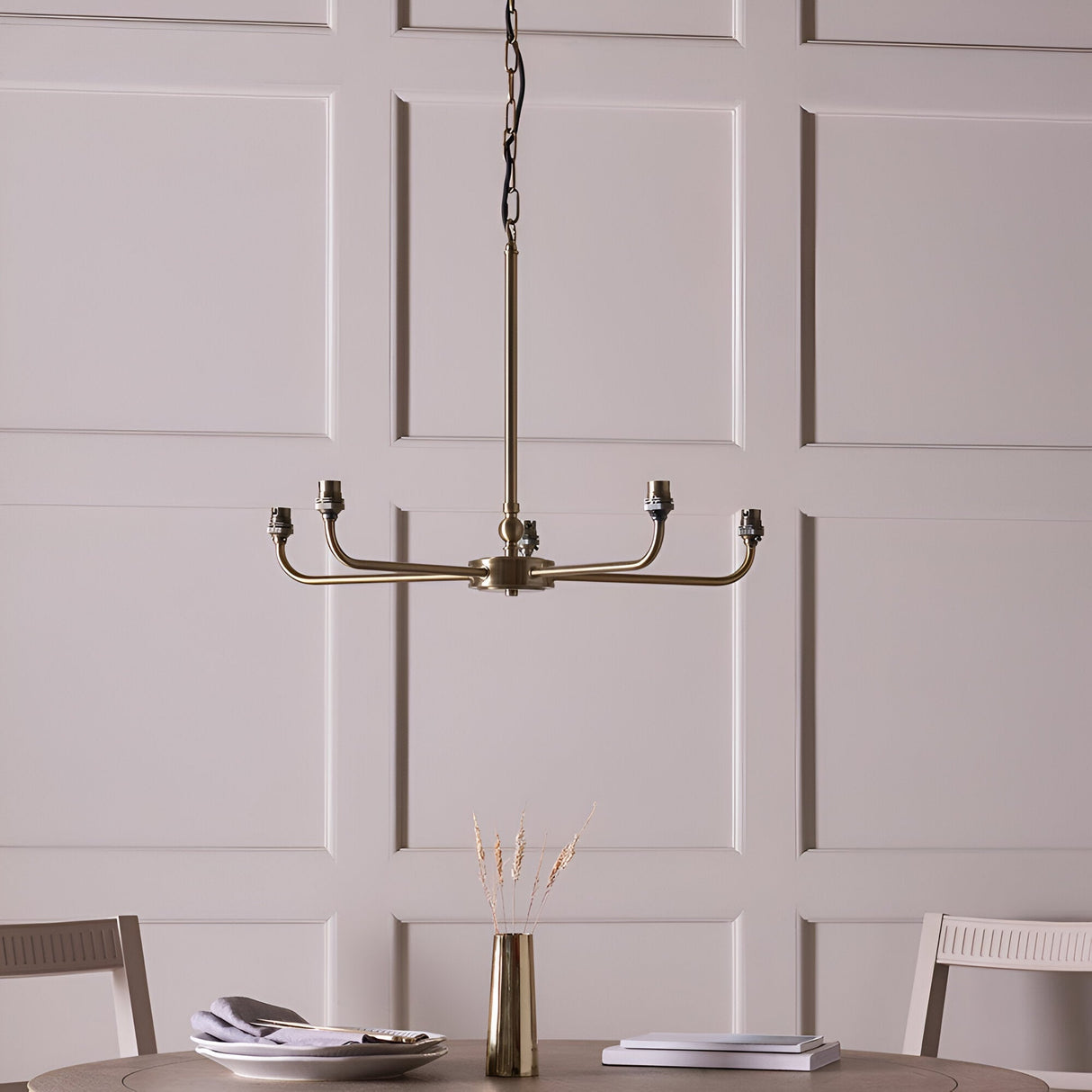Endon Caldmere five light pendant with antique brass arms and B22 lamp holders, shown without shades above a dining table against a panelled wall.