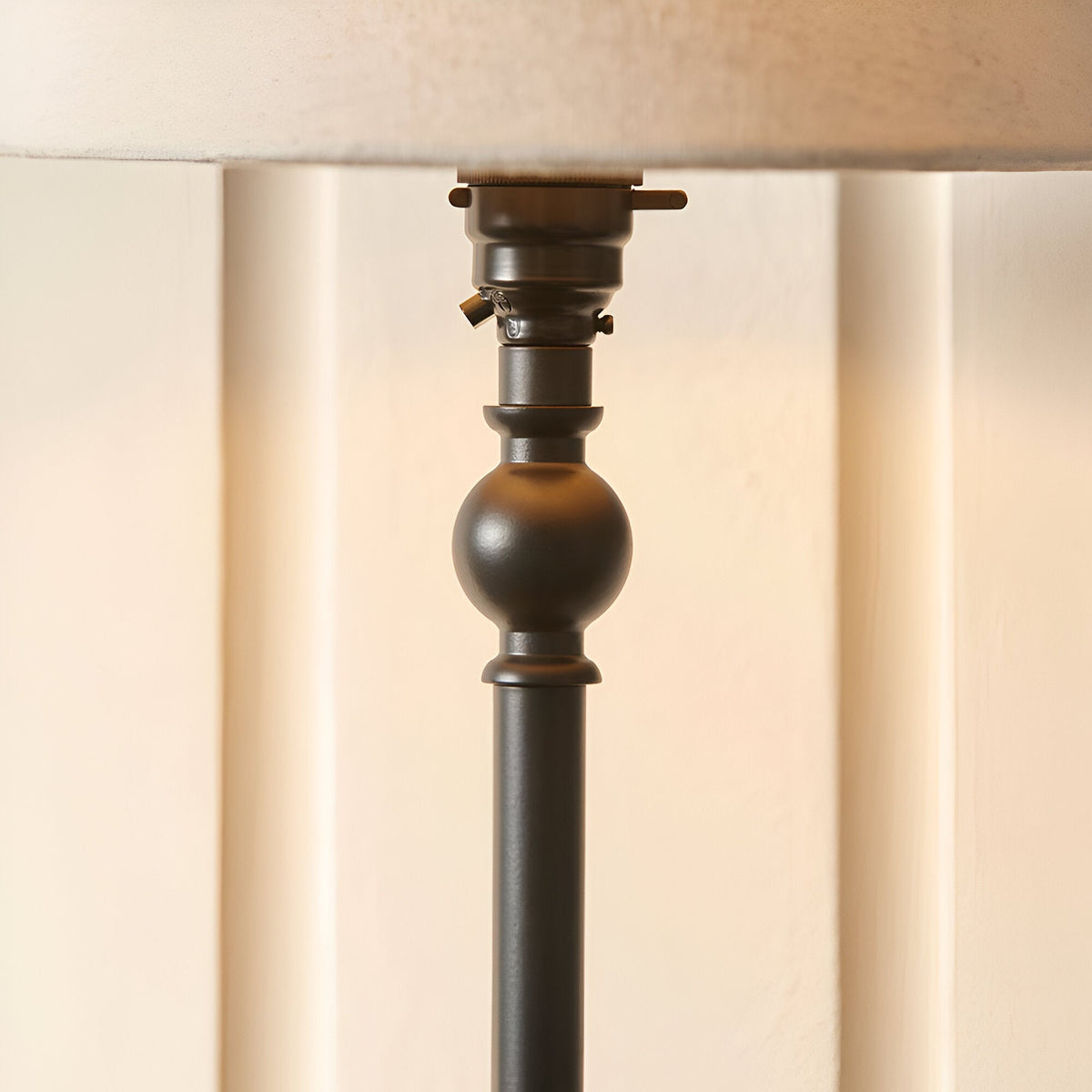 Endon Caldmont table lamp close-up showing matt black candlestick column with turned ball detail, switched B22 holder, and natural linen shade.