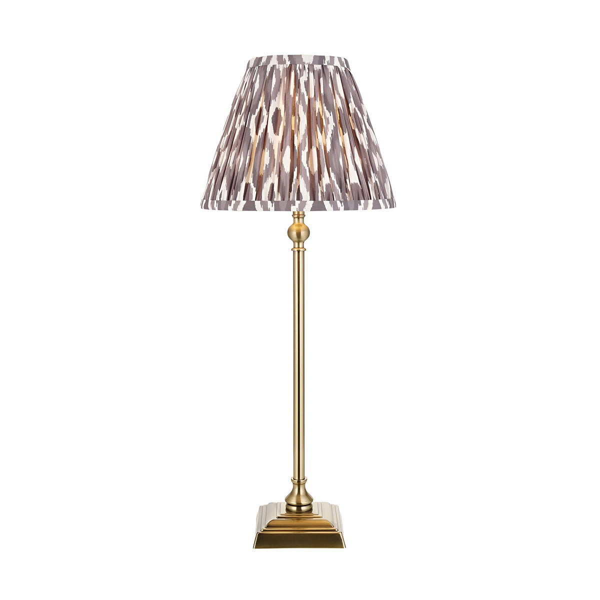 Endon Caldmere table lamp with slim antique brass candlestick base and pleated grey Ikat print fabric shade, shown on a plain white background.