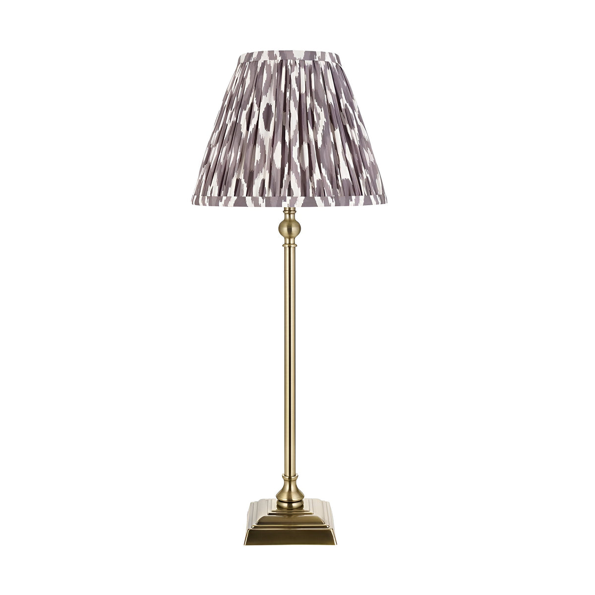 Endon Caldmere table lamp with slim antique brass candlestick base and pleated grey Ikat print fabric shade, shown on a plain white background.