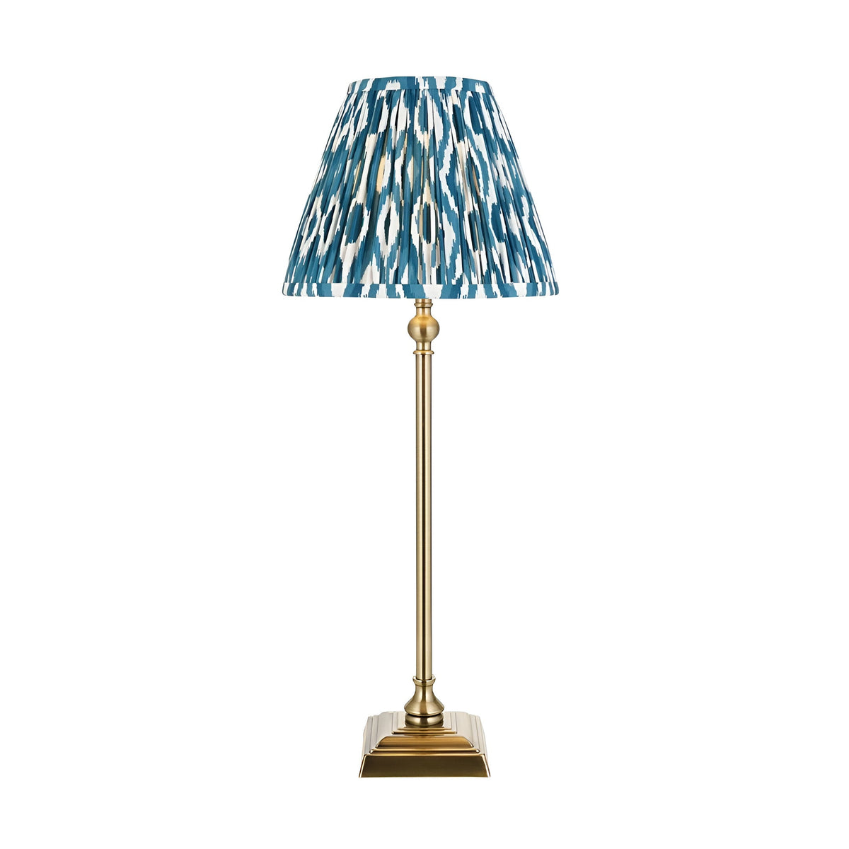 Endon Caldmere table lamp with slim antique brass candlestick stand and pleated blue ikat-print fabric shade, shown on a plain white background.