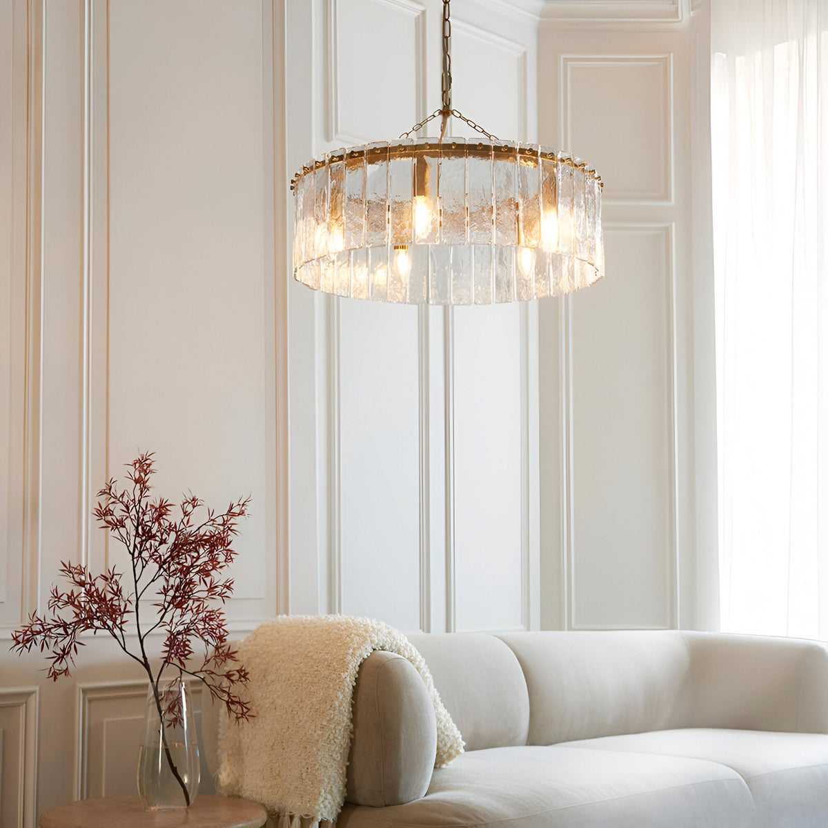 Endon Brockhurst 5 light pendant in brass with a ring of textured glass panels, hung from a chain above a cream sofa in a panelled living room.