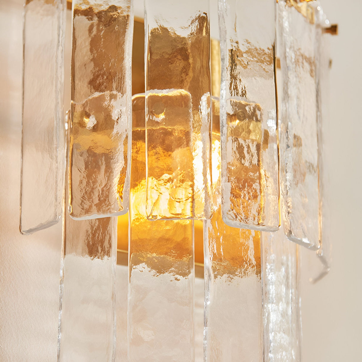 Close-up of the Brockhurst Wall Light in brass, showing layered handmade textured glass panels on a brushed aged brass backplate, glowing warm light.