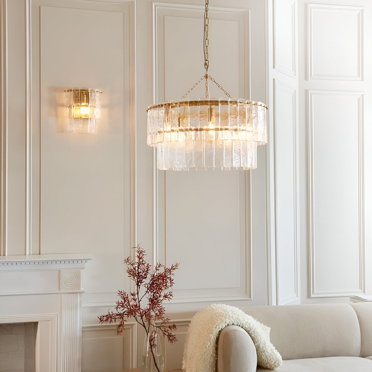 Brockhurst Wall Light in Brass with layered textured glass panels, illuminated on a panelled wall in a living room setting alongside a matching pendant light.