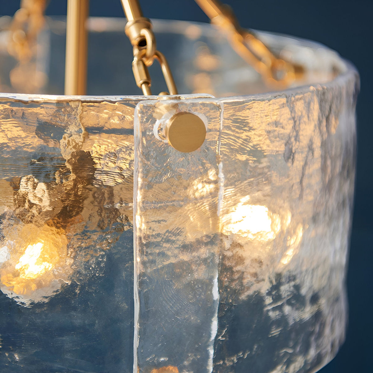 Close-up of the Brockmont 4 Light Pendant, showing thick rippled glass panels joined with brass fixings and a warm metallic frame.