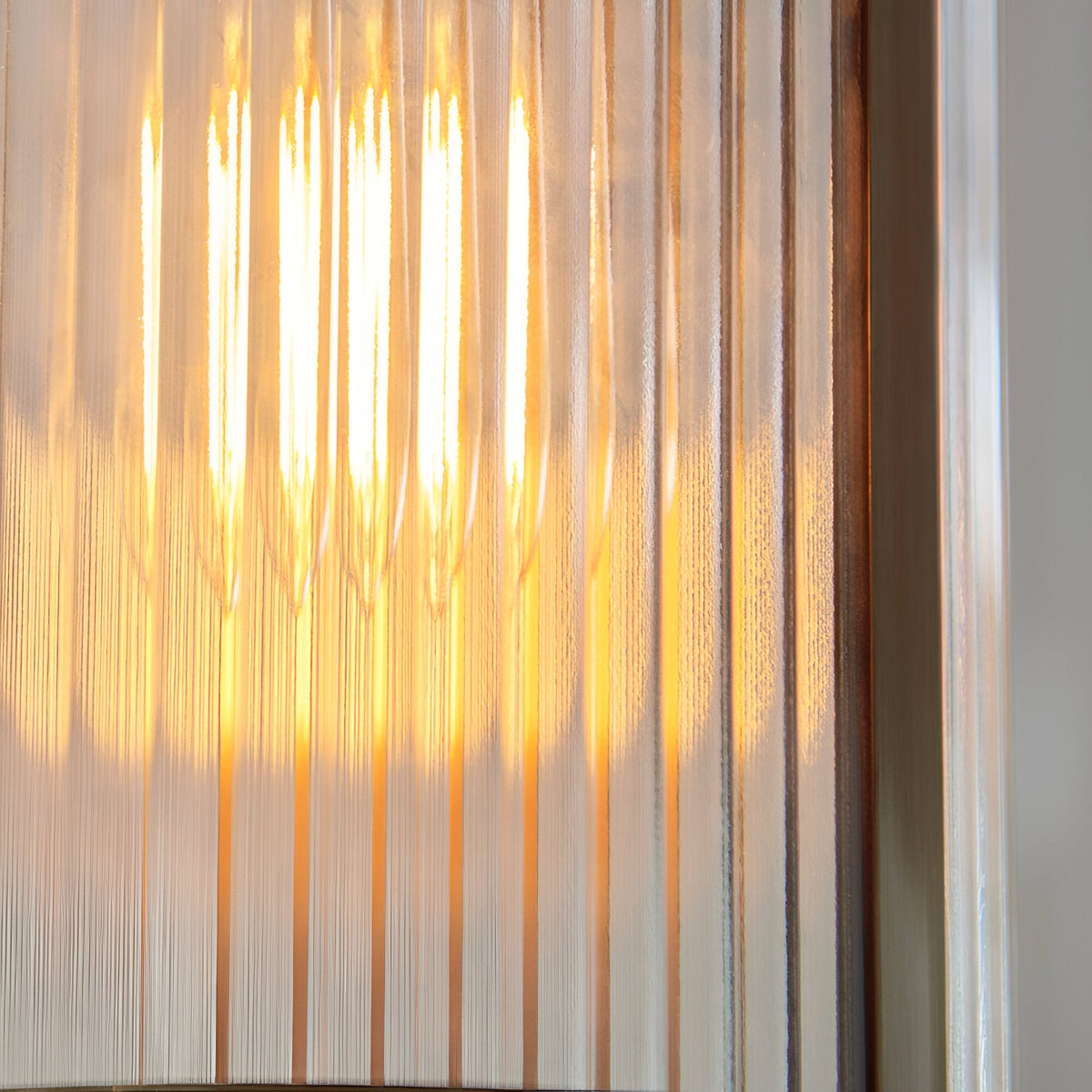 Close-up of the Endon Rothbury pendant's vertically ribbed clear glass shade with a warm E27 filament lamp glowing behind the textured cylinder.