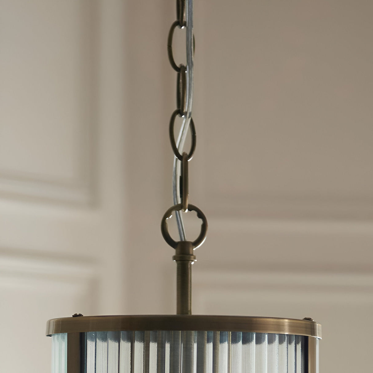 Close-up of Endon Rothbury Pendant in antique brass, showing chain suspension and top of ribbed clear glass cylindrical shade.
