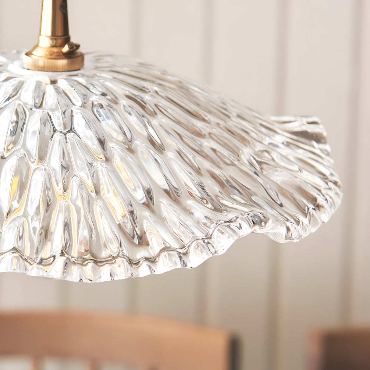 Close-up of the Endon Castshaw pendant shade in heavy clear glass with a rippled, shell-like texture and brass lamp holder fitting.