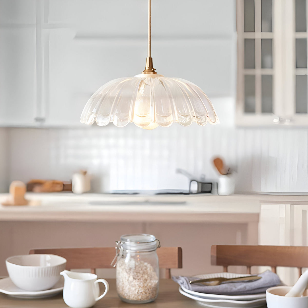 Endon Bevcombe clear glass pendant shade with scalloped domed form and brass fitting, hung above a kitchen island and dining table setting.