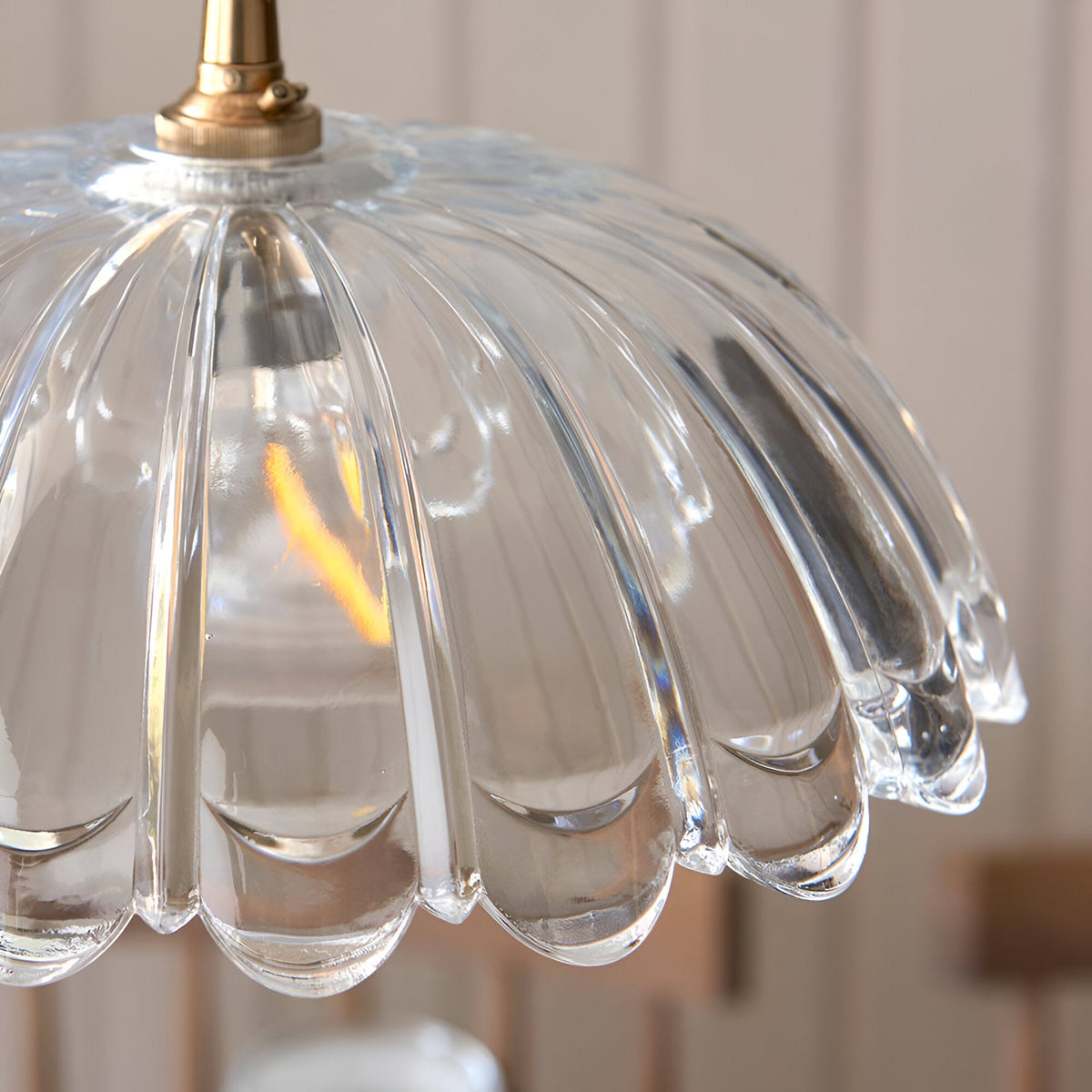 Close-up of Endon Bevcombe clear glass pendant shade showing scalloped domed form with ribbed detail and brass lamp holder fitting.