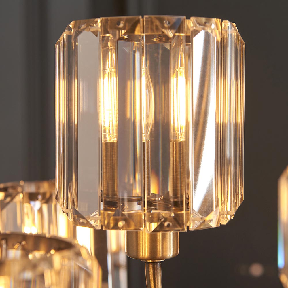 Close-up of the Clementine 9 Light Tiered Chandelier, showing faceted glass shades with antique brass fittings and lit E14 bulbs.