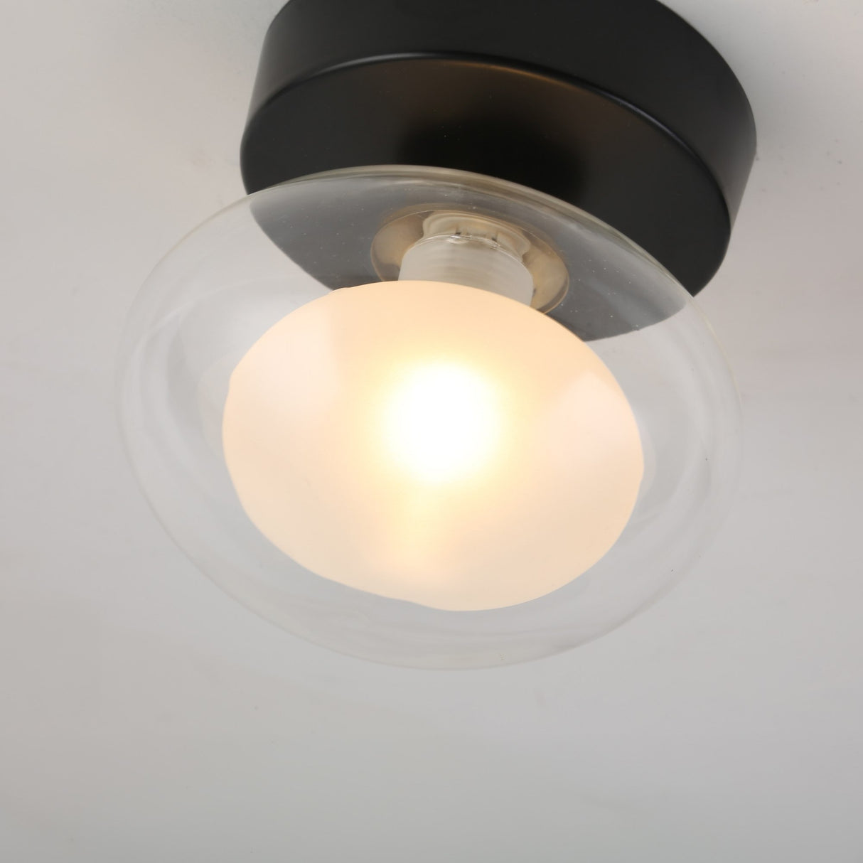 The Galaxy 1 Light Wall/Flush Ceiling Light - Black & White features a retro round black and white fixture with a clear glass globe and glowing bulb, mounted on a sleek black base for ceiling or wall use.