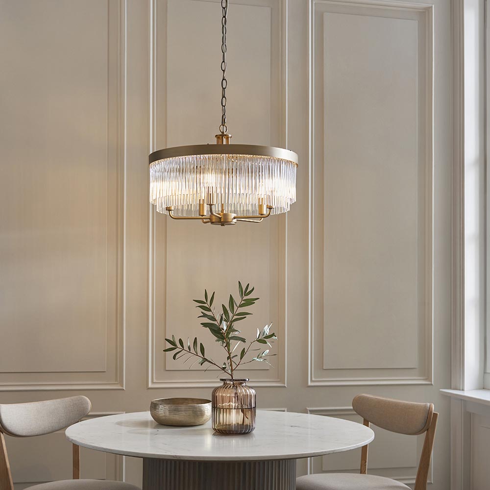Endon Chatsworth 5 light pendant in antique brass with double tier of clear glass rods, hanging above a round marble dining table.