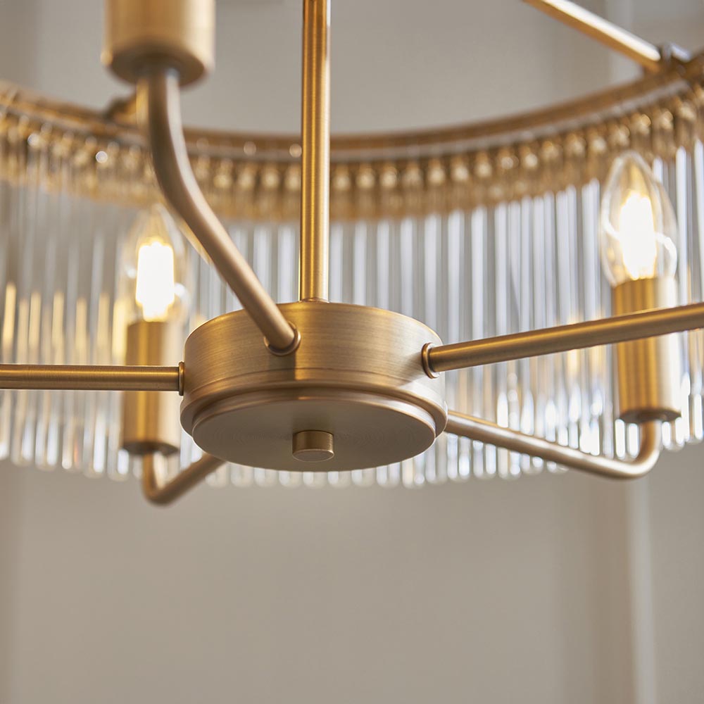 Close-up of the Endon Chatsworth 5 Light Pendant in antique brass, showing the hub, curved arms, and double layer of clear glass rods with lit E14 bulbs.