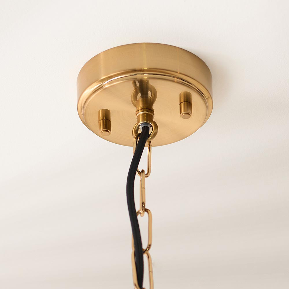 Close-up of Endon Haddon Grand Pendant brushed brass ceiling rose with two set screws, hook fixing, black fabric flex and brass chain link.