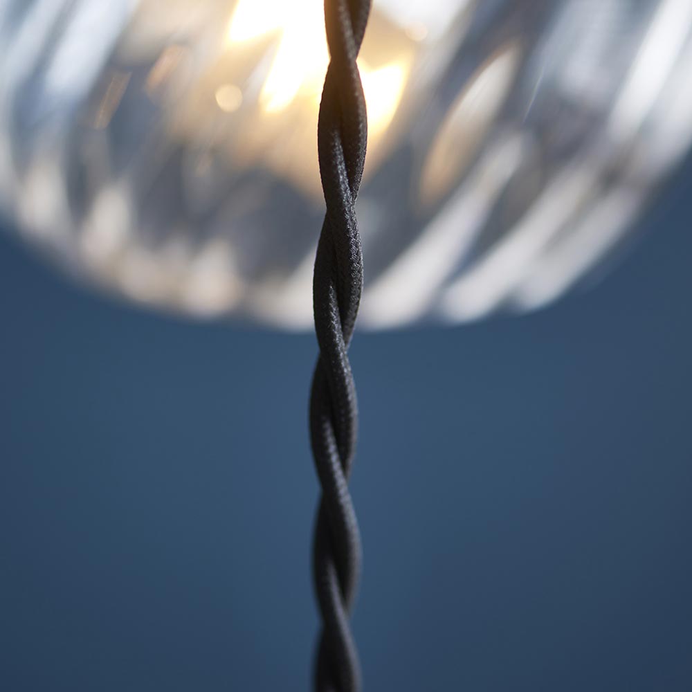 Close-up of the Endon Georgiana cascade pendant's black twisted fabric cable with a spiral glass shade and warm bulb glow softly blurred above.