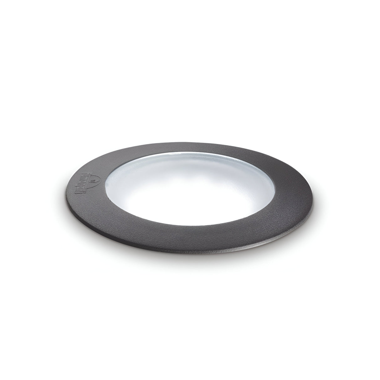 A circular black rubber gasket featuring a transparent center is placed against a simple white backdrop. It boasts a flat design, perfect for use with the Brass Small Round Outdoor Recessed Ground Light - Grey. An understated embossed logo adorns the upper left edge of the gasket, which promises durability and compatibility with IP67 rating standards.