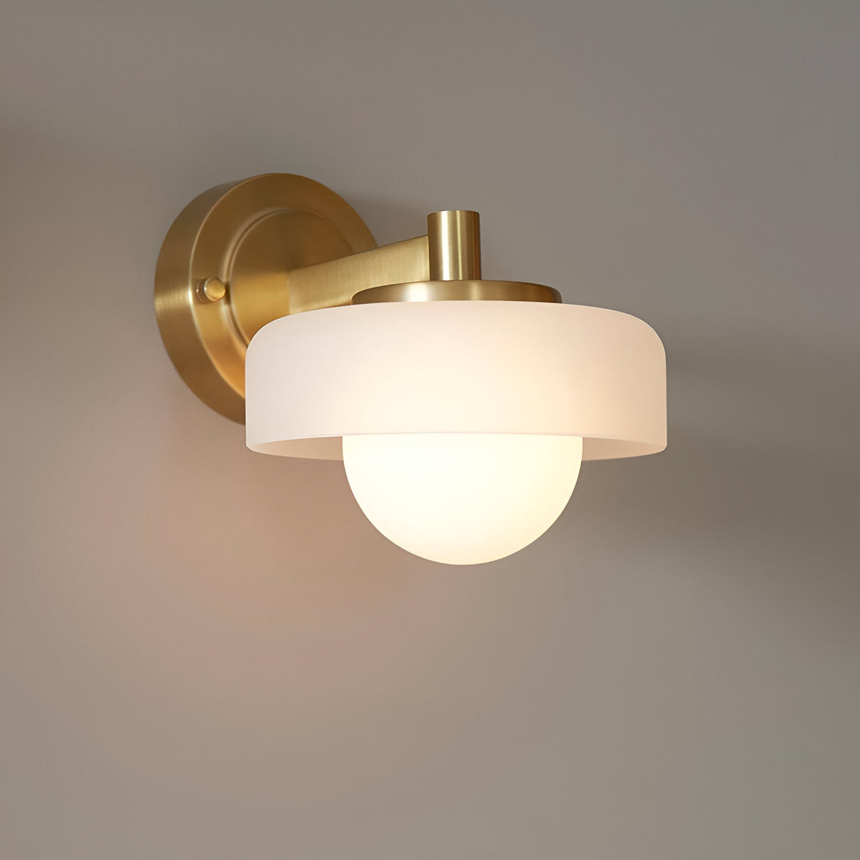 Endon Ashby wall light in brushed brass with a frosted glass drum shade and matt opal glass sphere, mounted on a light neutral wall.