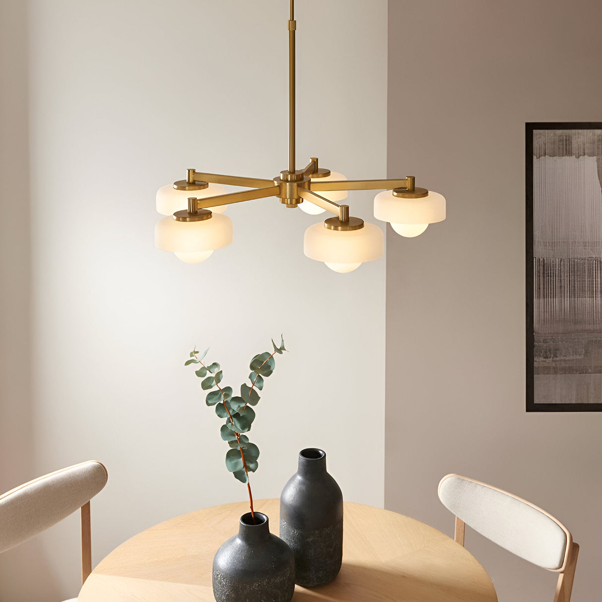 Endon Ashby 5 Light Pendant in brushed aged brass with frosted glass shades and opal inner globes, hung above a dining table with vases.