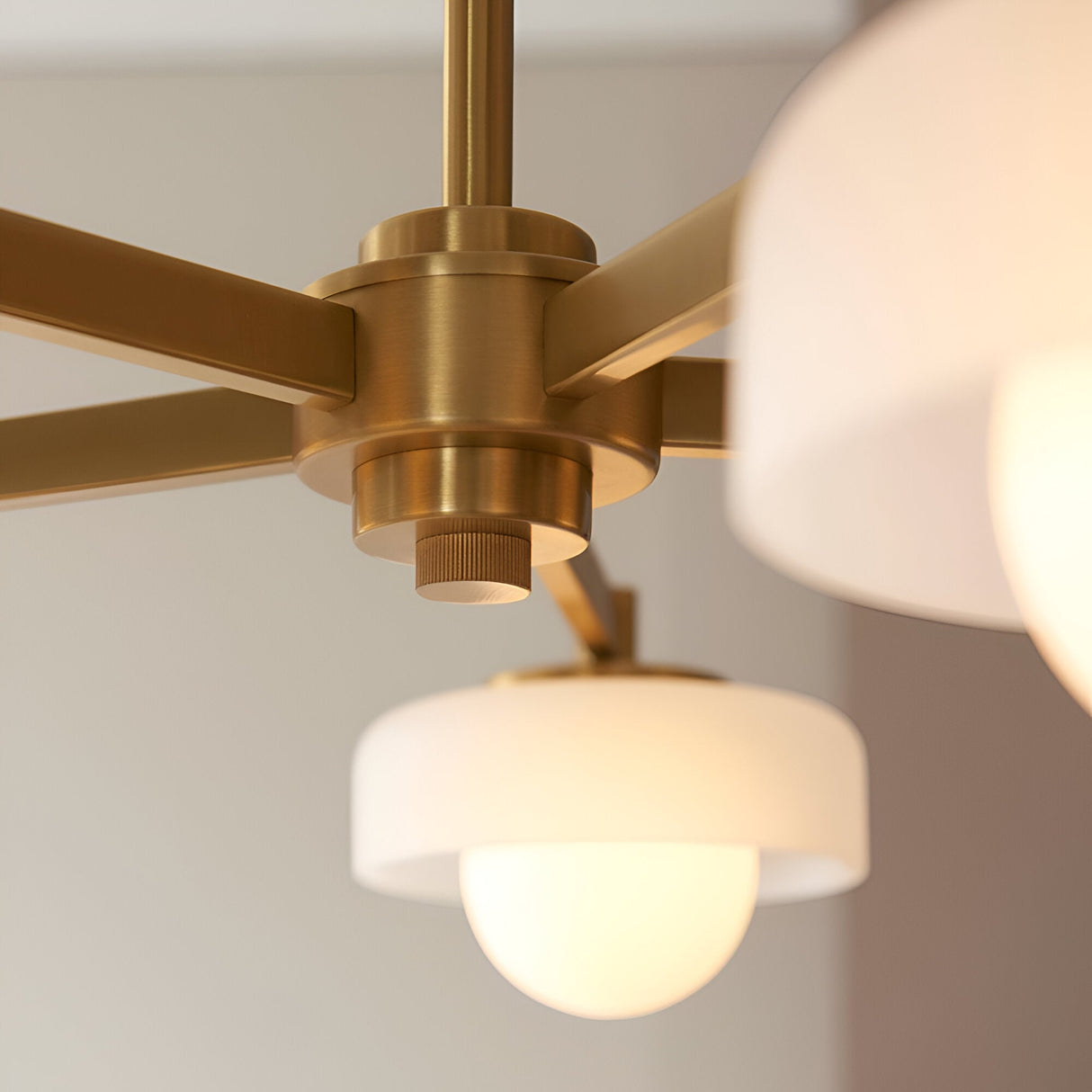 Close-up of the Endon Ashby 5 Light Pendant in brushed aged brass, showing the central hub, radiating arms and frosted glass shades with opal inner globes.
