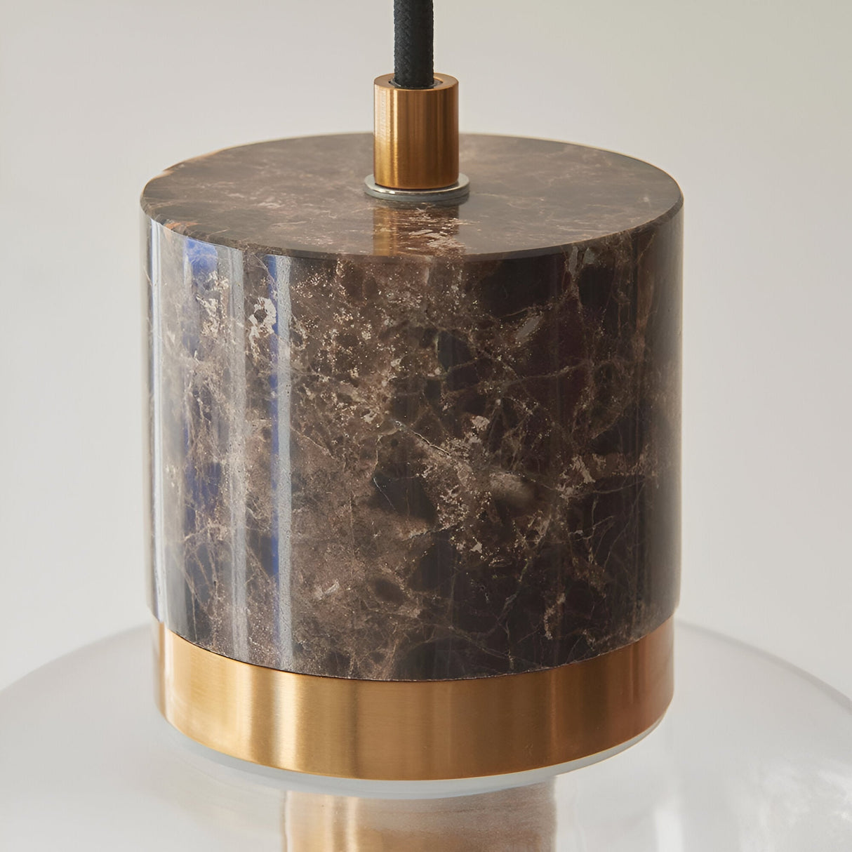 Cranstead Pendant Light with brown marble cylinder top, brushed brass collar, and clear glass shade on black fabric flex, shown on a white background.